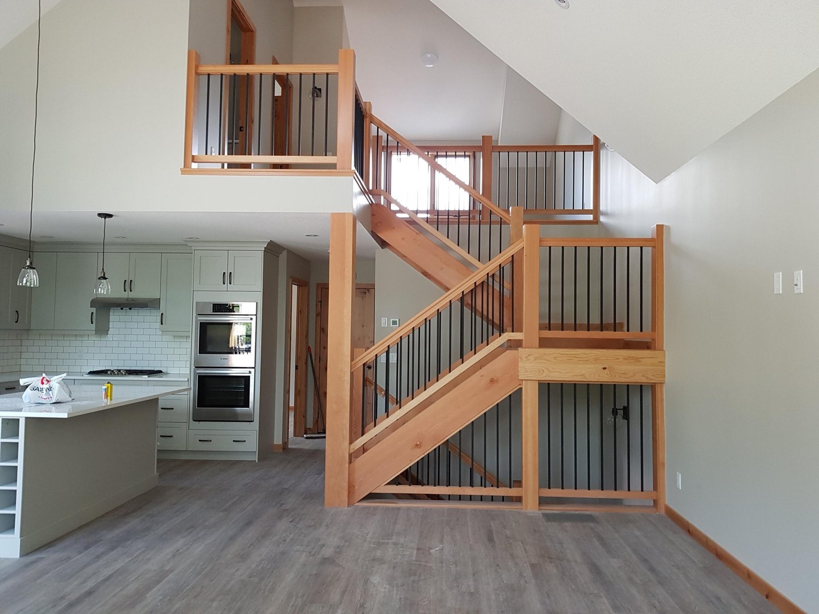 Custom wood staircase and railing with black spindles overlooking an open kitchen