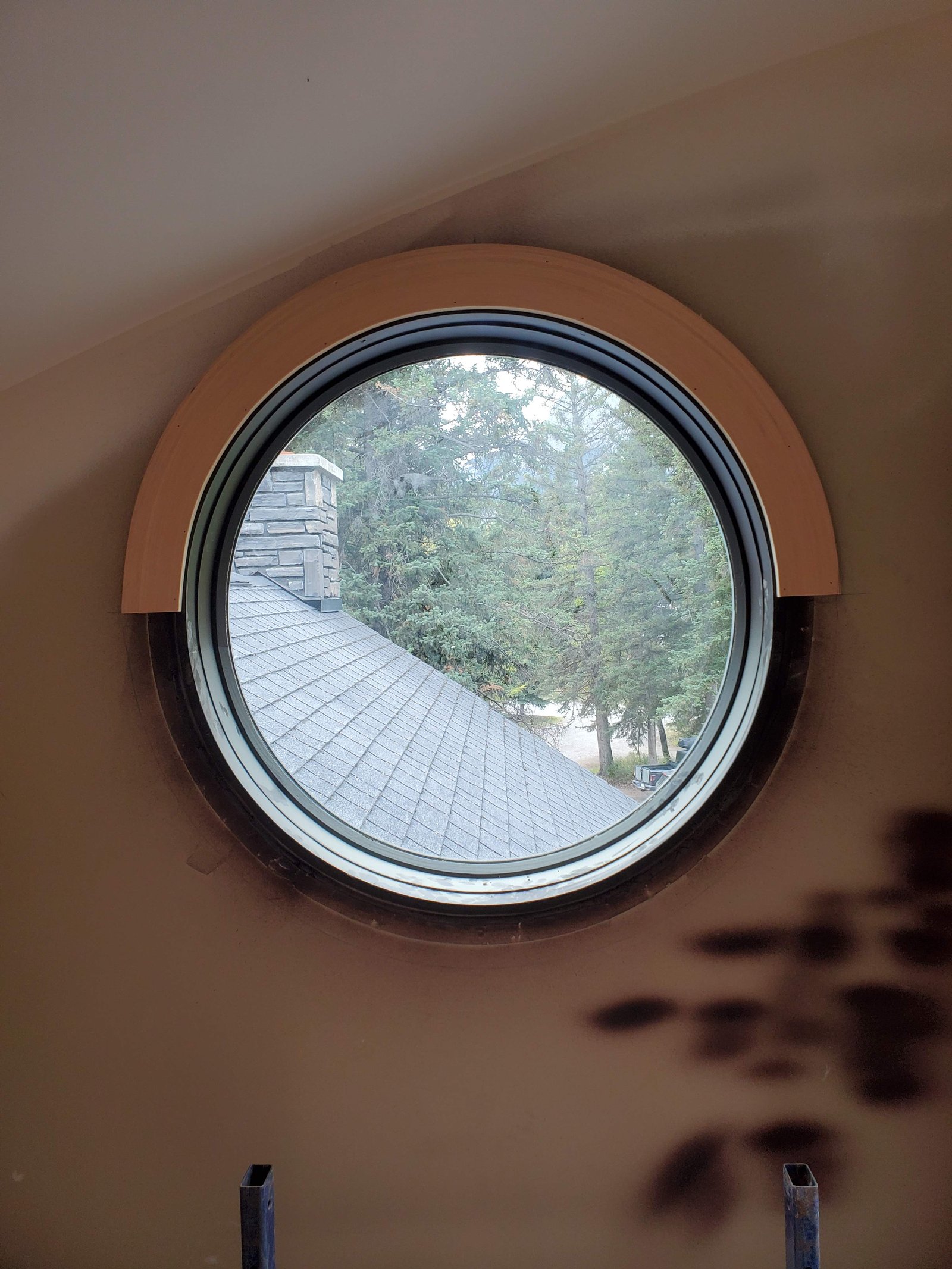 Custom round porthole window with wood casing in a sloped wall