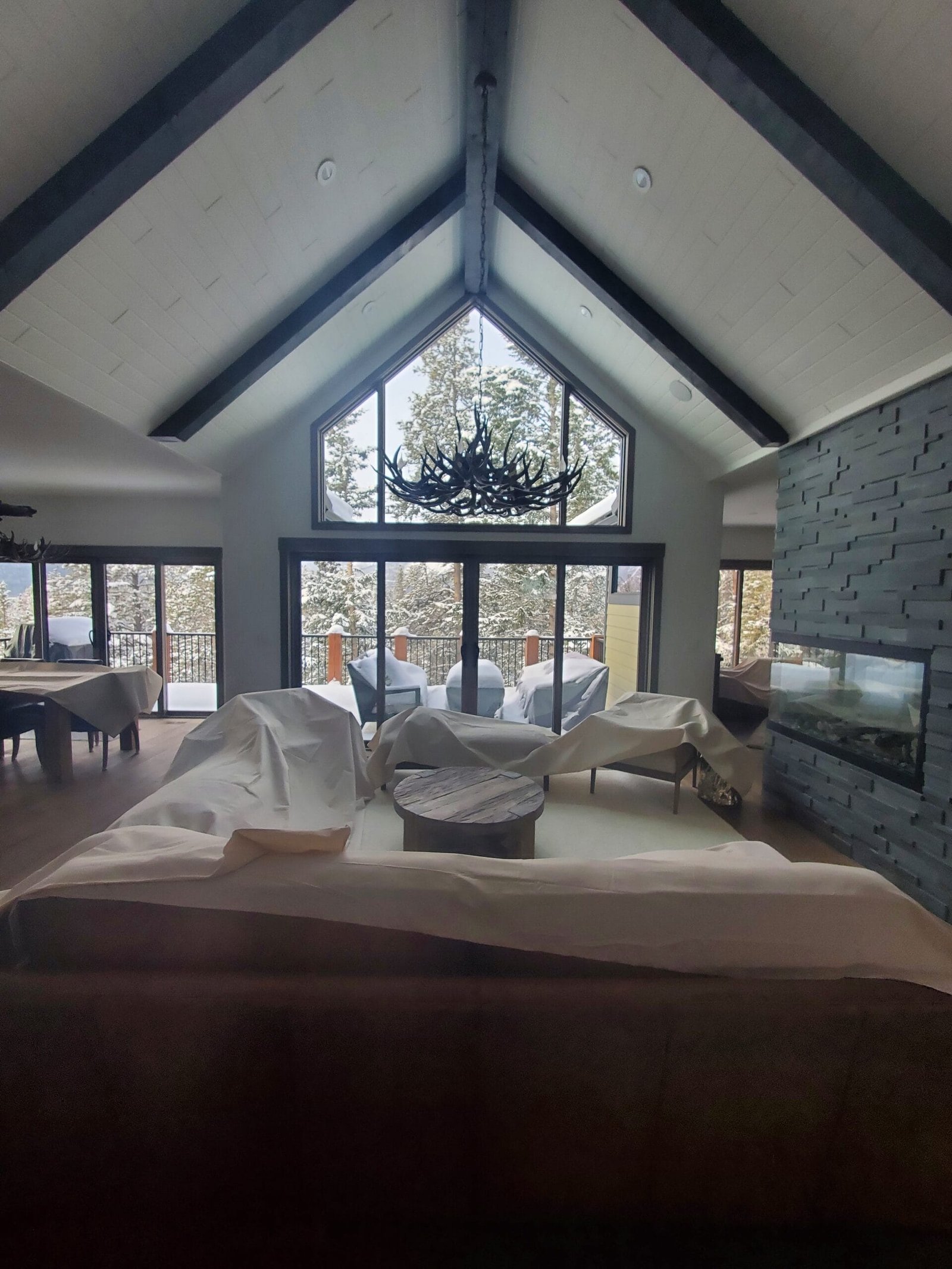 Vaulted living room with custom wood beams antler chandelier and stone fireplace