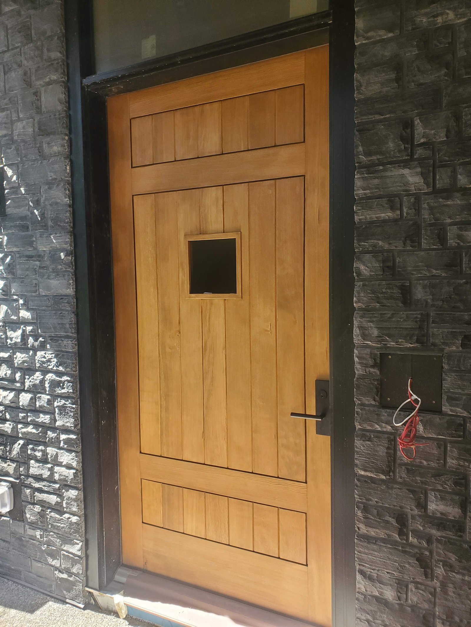 Custom wood entry door with recessed panelling set in a dark stone surround