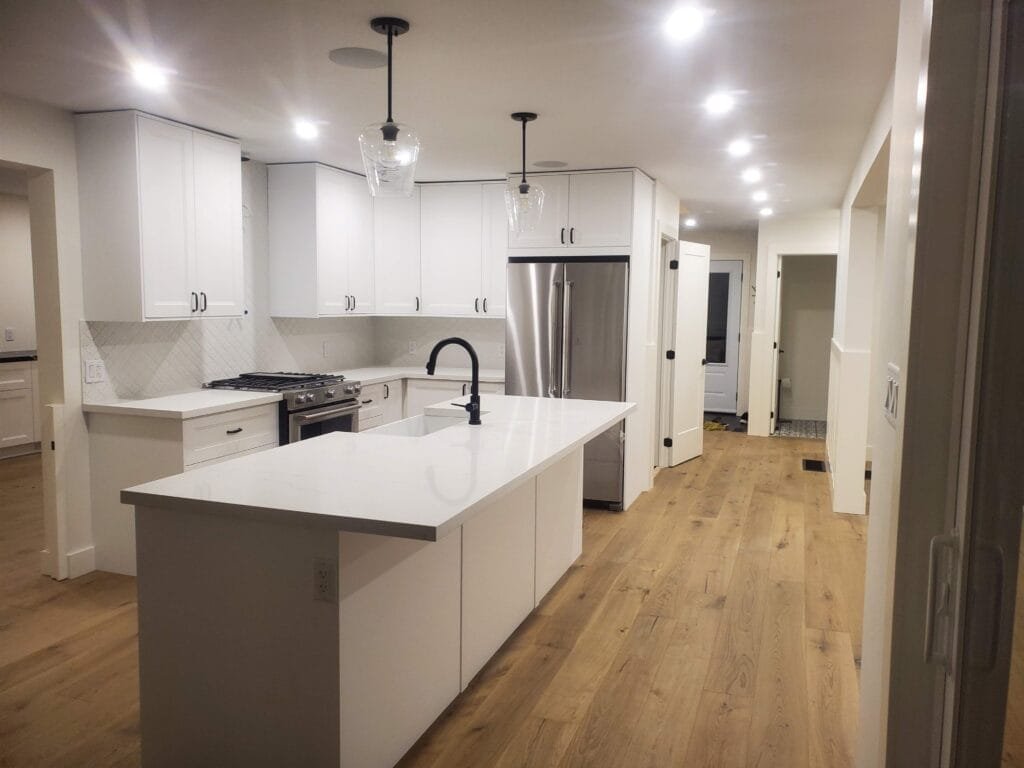 Complete custom kitchen with white shaker cabinets quartz island and pendant lighting