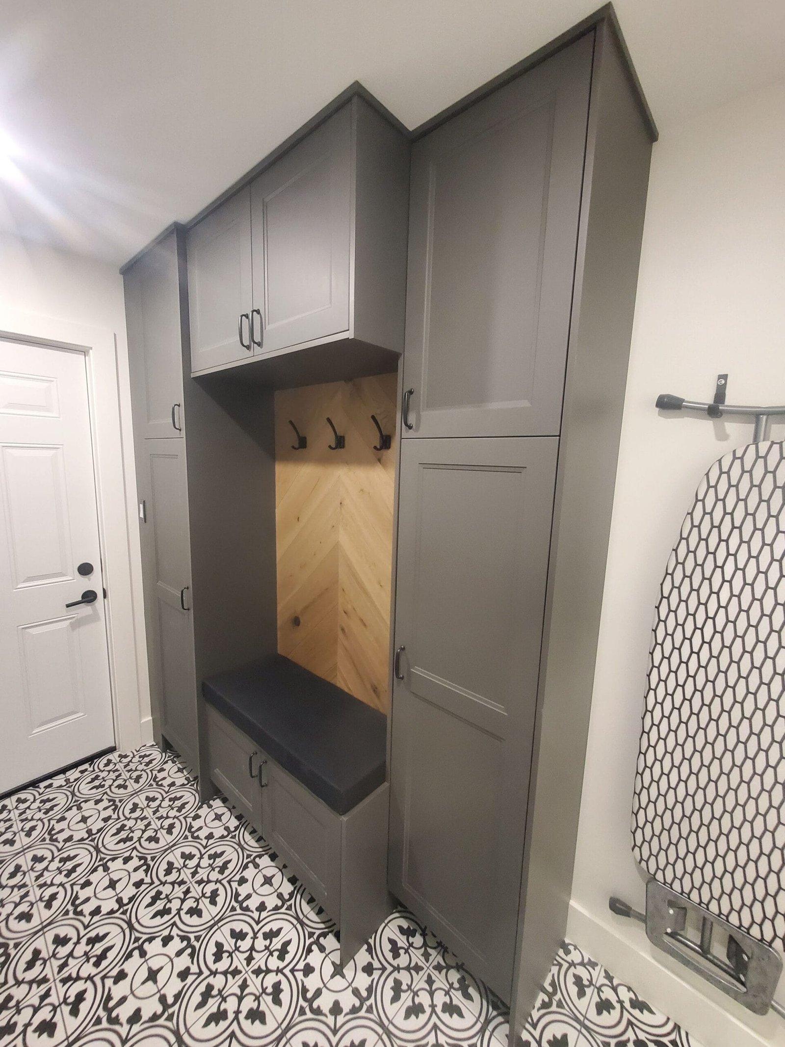 Custom mudroom cabinetry with herringbone wood back panel