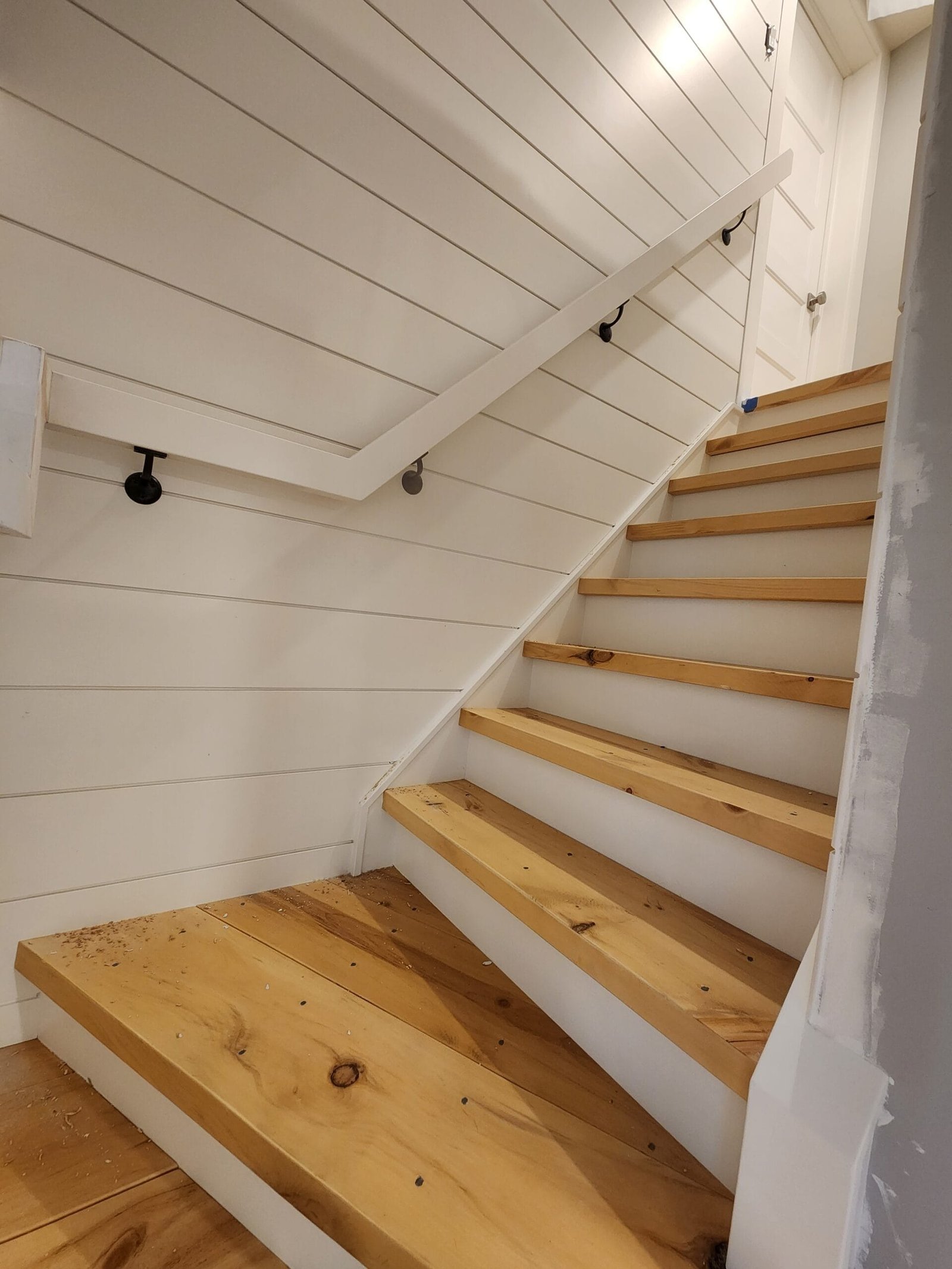 Custom staircase with natural wood treads and white shiplap wall panelling