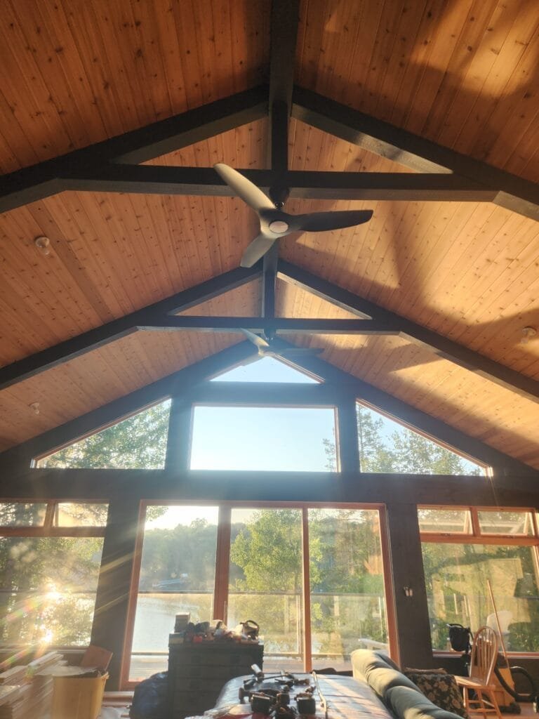 Vaulted pine ceiling with dark painted structural beams in cottage great room