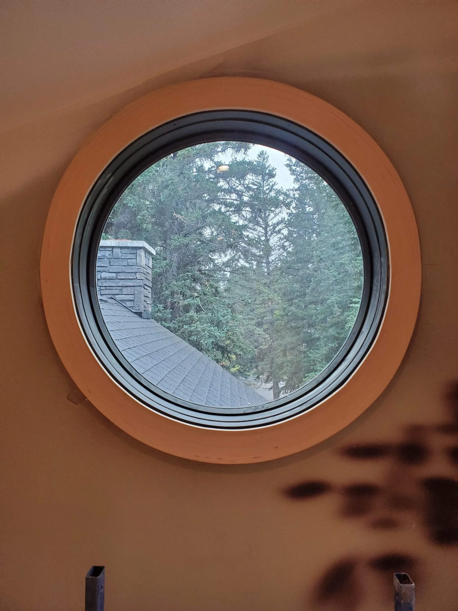Custom round porthole window with smooth wood casing trim by Dixon Custom Carpentry
