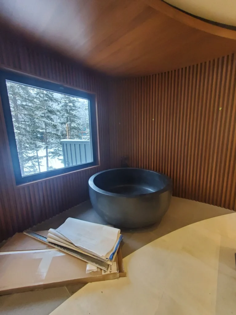 Custom slatted wood wall panelling surrounding freestanding soaking tub in Ontario home